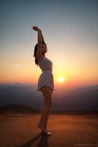 a spiritual seeker woman standing with outstretched arms, embracing the beauty of the sunrise or sunset, symbolizing gratitude and reverence for the universe