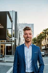 Happy smiling man on Hollywood movie set outside it is sunset in office clothes men's suit