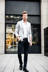 a confident masculine  man dressed in stylish attire, striking a pose in a trendy urban setting
