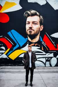 a fashionable masculine  man posing in front of street art