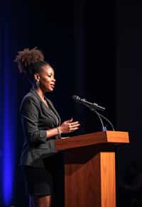 woman as a conference keynote speaker standing on stage at a conference