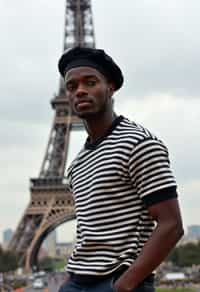 sharp and trendy man in Paris, wearing a beret and striped top, Eiffel Tower in the background