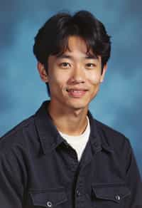 (school portrait) photo headshot of a young 18 y o man in 1990s style, nineties style, 90s, 1990s fashion, 1990s hair, school, man is sitting and posing for a (yearbook) picture, blue yearbook background, official school yearbook photo, man sitting (looking straight into camera), (school shoot), (inside), blue yearbook background