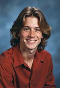 (school portrait) photo headshot of a young 18 y o man in 1990s style, nineties style, 90s, 1990s fashion, 1990s hair, school, man is sitting and posing for a (yearbook) picture, blue yearbook background, official school yearbook photo, man sitting (looking straight into camera), (school shoot), (inside), blue yearbook background