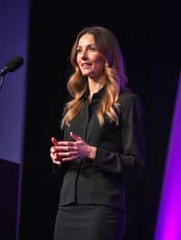 woman as a conference keynote speaker standing on stage at a conference