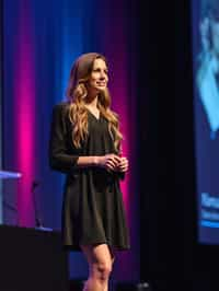 woman as a conference keynote speaker standing on stage at a conference