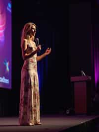 woman as a conference keynote speaker standing on stage at a conference