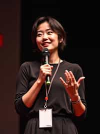 TedX speaker woman holding microphone with lanyard around his neck