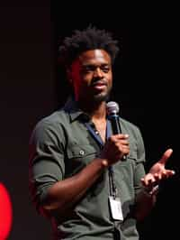 TedX speaker man holding microphone with lanyard around his neck