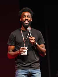 TedX speaker man holding microphone with lanyard around his neck