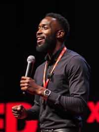 TedX speaker man holding microphone with lanyard around his neck