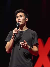 TedX speaker man holding microphone with lanyard around his neck