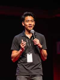 TedX speaker man holding microphone with lanyard around his neck