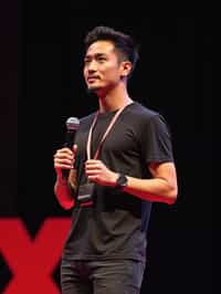 TedX speaker man holding microphone with lanyard around his neck