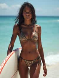 woman in high-waisted bikini  with surfboard on the beach, ready to ride the waves