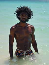 man in  swim shorts} in sea water on the beach, wet hair