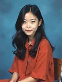 (school portrait) photo headshot of a young 18 y o woman in 1990s style, nineties style, 90s, 1990s fashion, 1990s hair, school, woman is sitting and posing for a (yearbook) picture, blue yearbook background, official school yearbook photo, woman sitting (looking straight into camera), (school shoot), (inside), blue yearbook background