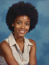 (school portrait) photo headshot of a young 18 y o woman in 1990s style, nineties style, 90s, 1990s fashion, 1990s hair, school, woman is sitting and posing for a (yearbook) picture, blue yearbook background, official school yearbook photo, woman sitting (looking straight into camera), (school shoot), (inside), blue yearbook background