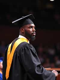 a graduate man in their academic gown at stage to receive their diploma