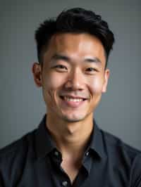 A professional actor headshot of a confident man, taken in a well-lit studio with a plain backdrop. The man is dressed in  a fitted dark-colored shirt with neatly styled hair. The lighting is soft and even, highlighting their facial features with a natural and approachable expression. The focus is sharp, capturing the man's eyes and subtle smile, creating a perfect headshot for auditions and casting calls.